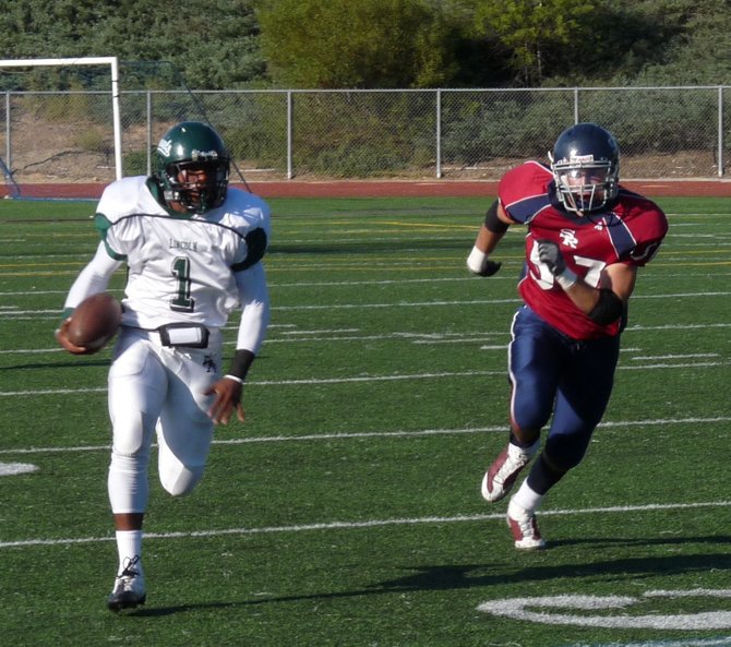 Lincoln quarterback Ronnie Yell runs downfield with Scripps Ranch's Taylor Stenman on his heels