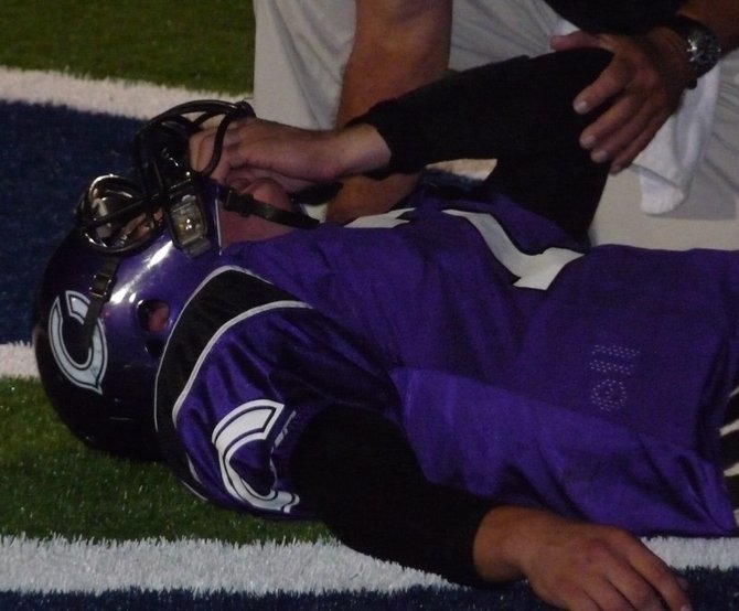 Carlsbad quarterback Michael Leonard winces in pain he receives treatment for leg cramps