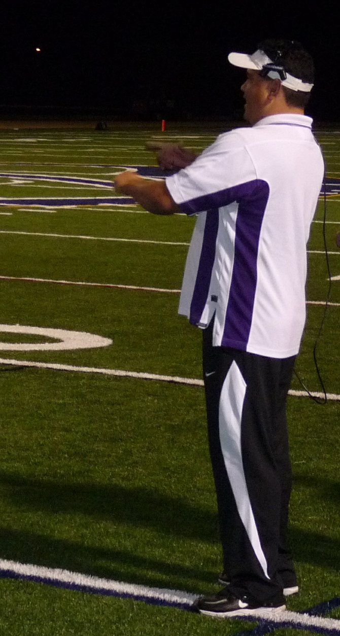 Carlsbad defensive coordinator Miguel Perez signals in a play from the sideline