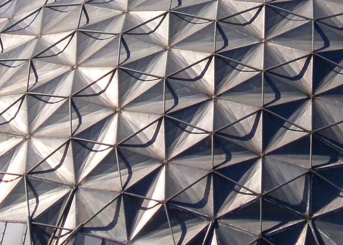 This is a closeup of the dome that covers the gymnasium at Palomar College. It is an example of a "Kaiser" geodesic dome because it was built by Henry J. Kaiser's company Kaiser Aluminum in 1959. That's the same fellow who came up with the concept of providing healthcare to workers at his factory and eventually founded Kaiser Permanente. The hexagonal-style geodesic dome at Palomar College was designed by Buckminster Fuller, who although he did not invent geodesic domes, he was the first person to record the mathematical computations and present them as a formula, and so became the person most associated with them. He received patent number 2682235 for his troubles.

