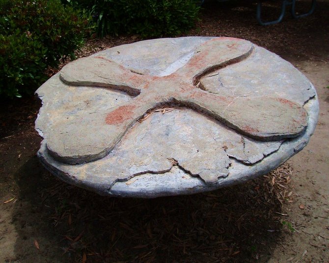 This concrete disc sculpture, according to Mira Costa's website, is attributed to one of its retired art professors, Howard Ganz. 