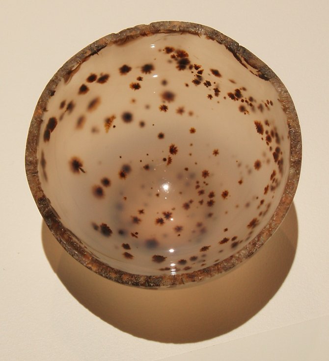 This is a bowl that's been carved from a single piece of moss agate in the All That Glitters jewelry exhibition at the San Diego Natural History Museum.