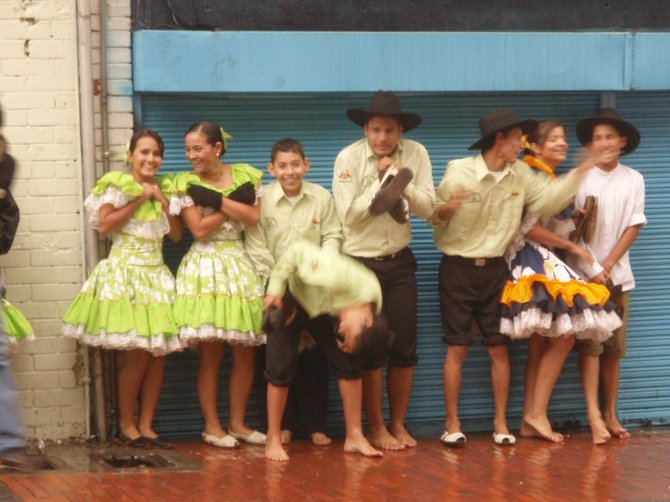 A dance troupe meant to dance in the streets as part of a festival takes refuge from the sudden rain in Bogota, Colombia