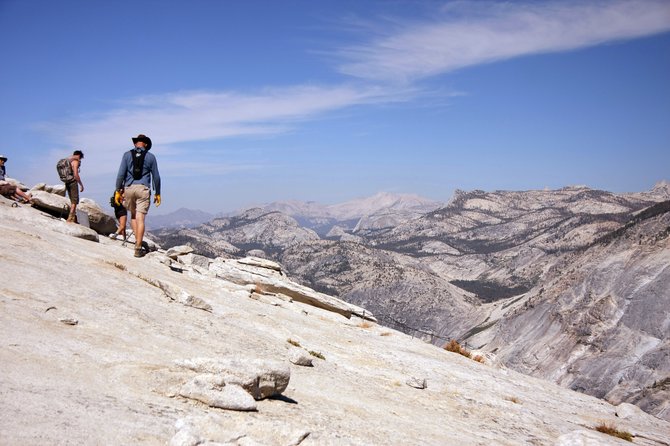 A view from the top of Half Dome as a hiker approaches the cables (visibile toward the lower right) to begin his descent.
