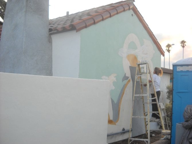 Gina Faulk painting a mural on the old Thee Bungalow parking lot wall.