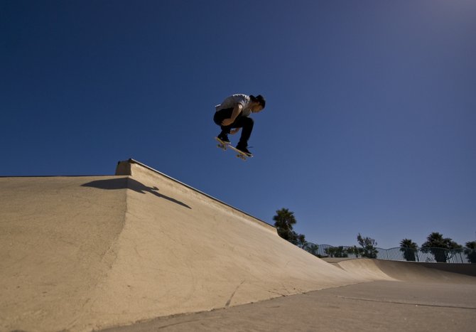 Under a crystalline cloudless blue sky of early spring at the OB skate park, Nathan Van Wormer goes airborne with a hip ollie.
