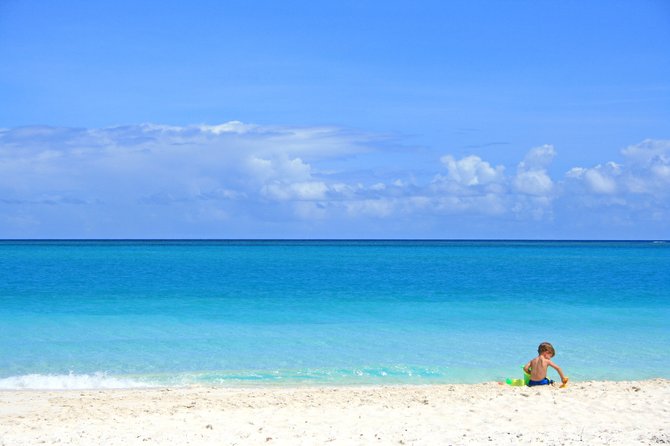 A small boy lets his imagination run wild while playing alone along Grace Bay Beach.