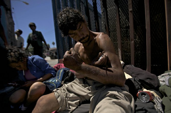 A Tijuana heroin addict shoots up near the border fence.