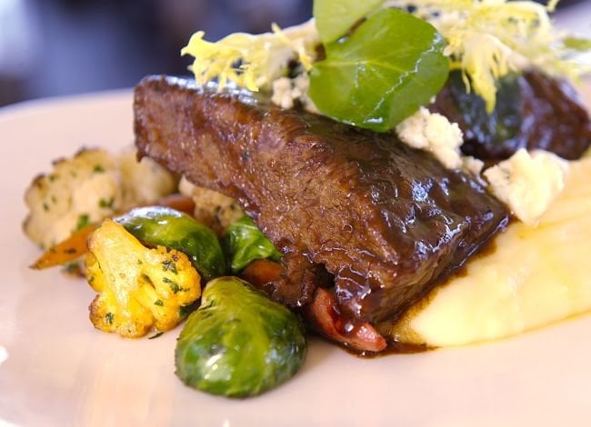 Braised short ribs with Yukon gold potatoes and roasted baby vegetables — you will eat well here, but the price is not casual.