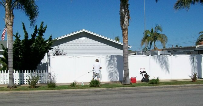 An Imperial Beach resident pressure-washes his fence that had been tagged with graffiti. 