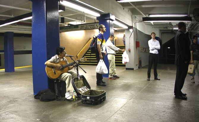 A musician earns a living while entertaining on the subway platform.