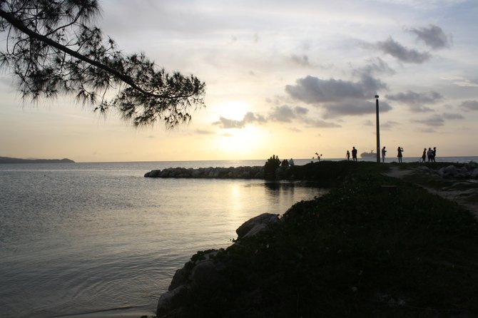 Onlookers watch the sun set over the stunning Caribbean Sea.
