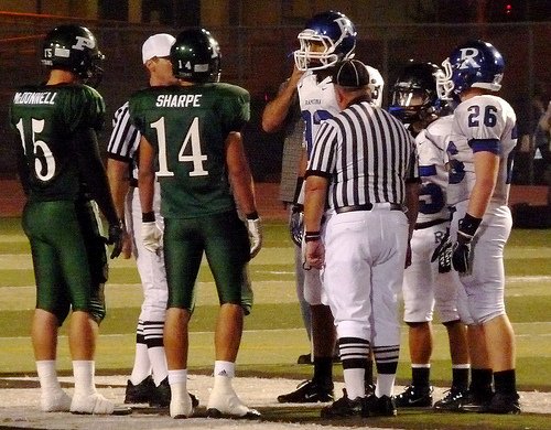 Poway and Ramona team captains meet at midfield for the coin toss