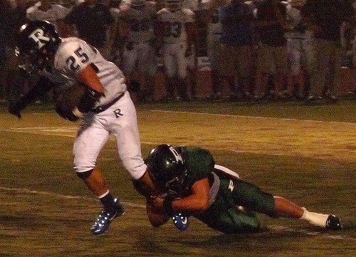 Ramona running back Nate Lutu lunges forward with a Poway defender hanging on