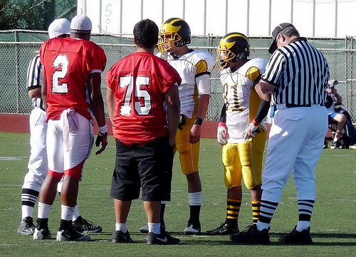 Hoover and Mission Bay team captains meet at midfield for the coin toss