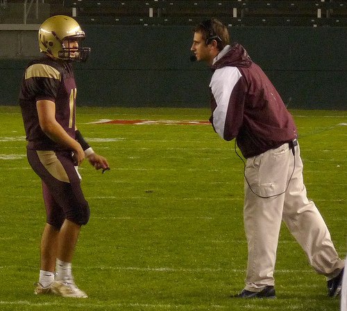 Bishop’s quarterback Joey Moreno gets the play call from Knights coach Joel Allen