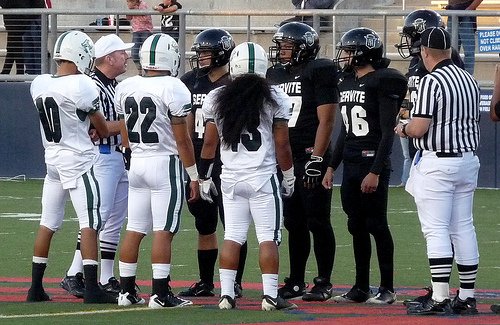 Oceanside and Servite team captains meet at midfield for the coin toss