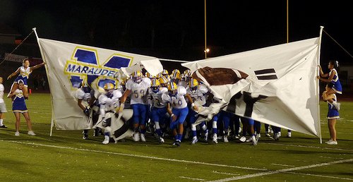 Mira Mesa players bust through the banner after halftime