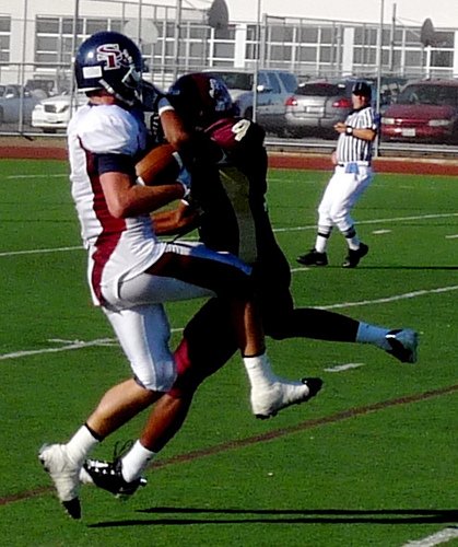 A Scripps Ranch receiver hauls in a pass with Point Loma defensive back Aaron Watkins draped all over him
