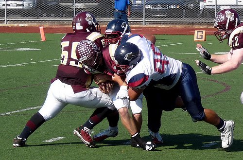 A pair of Steele Canyon defenders engulfs Point Loma quarterback Thomas Mize for a sack