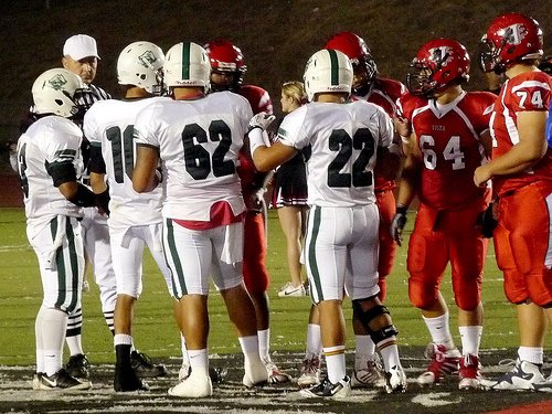 Oceanside and Vista team captains meet at midfield for the coin toss