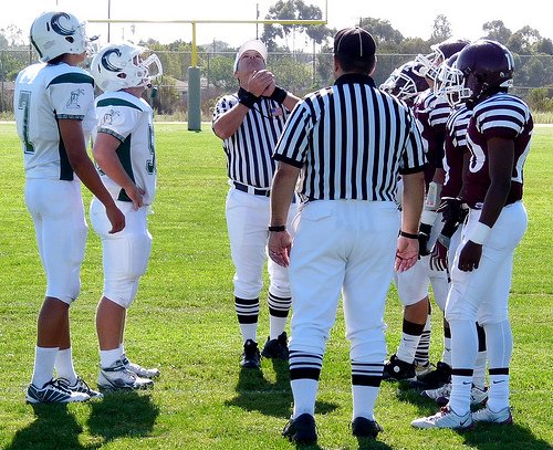 The referee tosses the coin as team captains from Coronado at Kearny look on