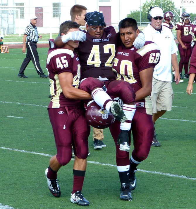 Point Loma running back Eric Bueno (42) carried off the field by Pointers linemen Andre Montano (45) and Jovanny Sanchez (60) after injuring his knee