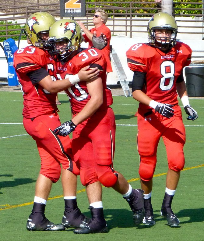 Santa Fe Christian running back Tony Miro (30) celebrates a touchdown run with Eagles lineman Connor Vaccaro (63) and receiver Cole Needham (8)