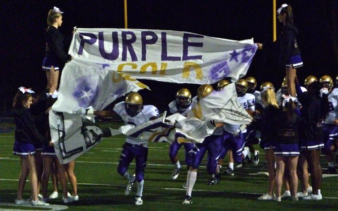 St. Augustine players rip through the banner after halftime
