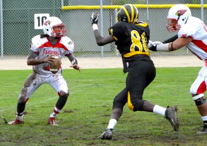 Hoover quarterback Dionte Whitfield looks for a receiver downfield as Mission Bay lineman TJ Gatdoar rushes in