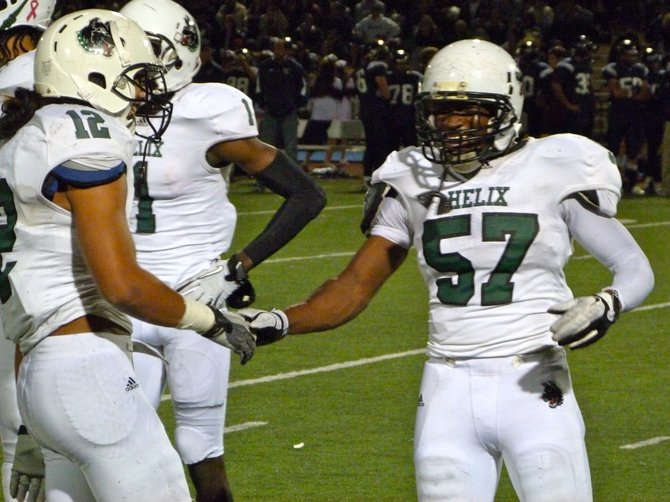 Helix linebacker Ernest Shipley (57) shares a laugh with Highlanders linebacker Rocky Fuga during a timeout