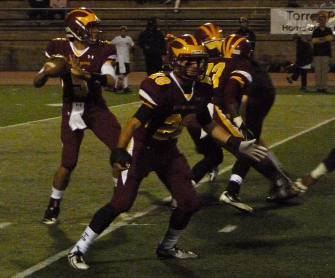 Torrey Pines quarterback Andrew Perkins looks for a receiver from the pocket with Falcons running back Collin Brown blocking