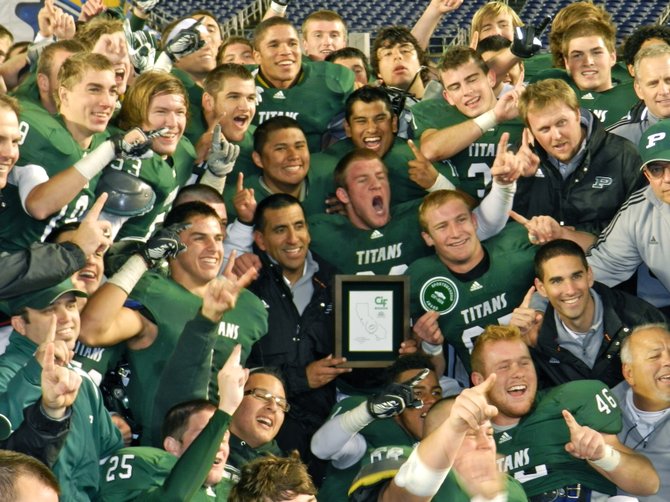 Poway players surround head coach Damian Gonzalez and the Division I championship plaque following the Titans' victory