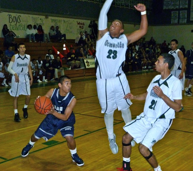 San Marcos guard Mark Pacia drives to the hoop against Oceanside guards Tofi Pao Pao (23) and Justin Gilbert (21)