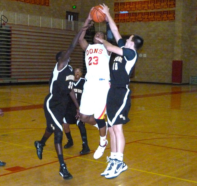 Cathedral Catholic forward Xavier Williams elevates for a shot between Mission Bay forwards T.J. Gatdoar (left) and Dylan Holler