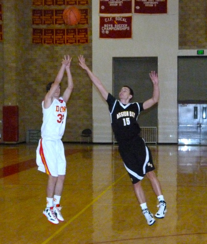 Cathedral Catholic guard Parker Holland fires a three-pointer over Mission Bay forward Dylan Holler