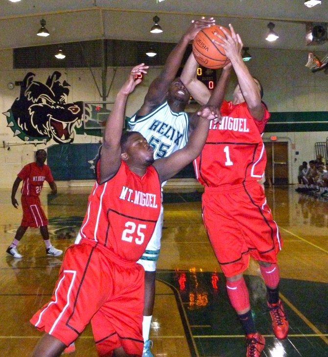 Mount Miguel guard Izzy Wagner grabs a rebound over Helix forward Kene Anigbogu and a Matadors teammate 