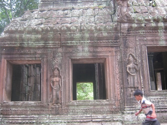 A little boy runs past ancient ruins at Angkor Wat, Cambodia.