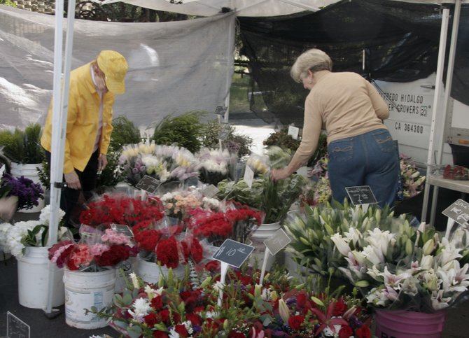 Shoppers choosing flowers at the Hidalgo Flower booth at the Farmer's Market at the Bernardo Winery in Rancho Bernardo.