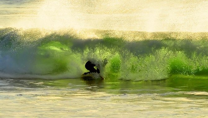 The sun shines through the back of this wave and illuminates the surfer at Marine Street, La Jolla.