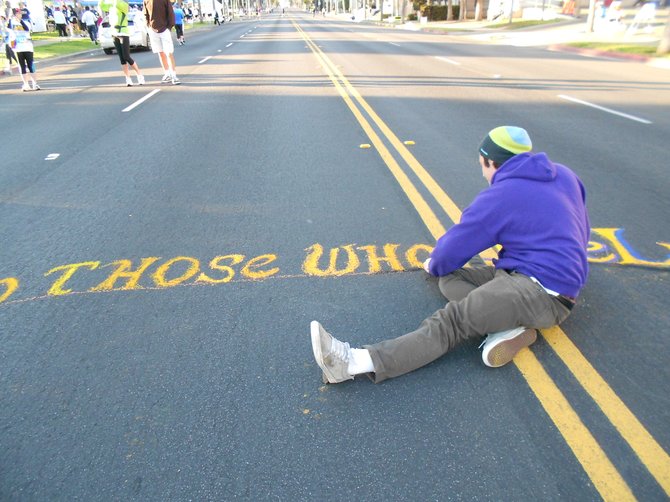 Street sign chalk artist creating a message at charity run in Balboa Park.