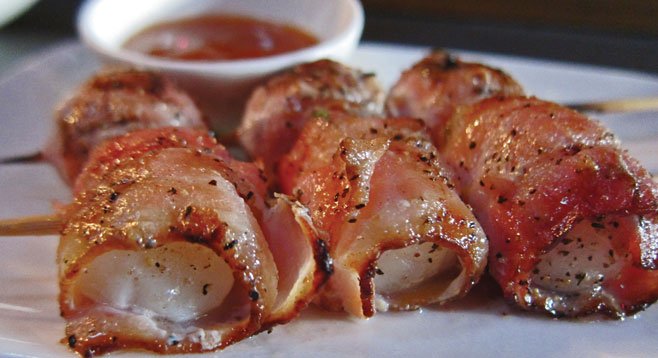 Nueske bacon enrobes skewers of sweet scallops.