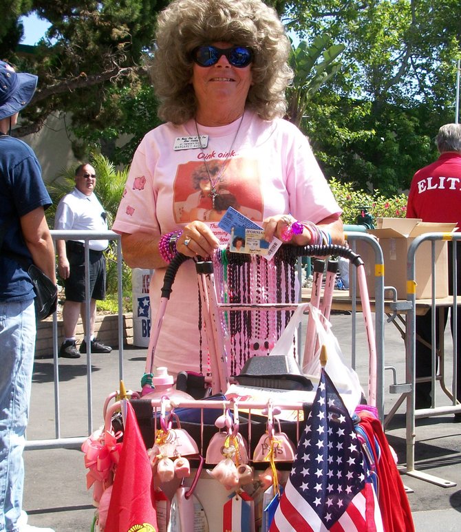 The San Diego County Fair opened its gates at 11:00 a.m. on Friday, June 8. Margaret Austin of Escondido was the first person in line at the official gate, and has been for at least the last 25 years. She boarded a bus in Escondido at 5:30 a.m. to arrive by 7:30. Her walking cart was filled with pig memorabilia. She comes each year to see the "piggies." Her T-shirt was custom made for her by the Swifty Swine Pig Racers, a popular show at the fair. 