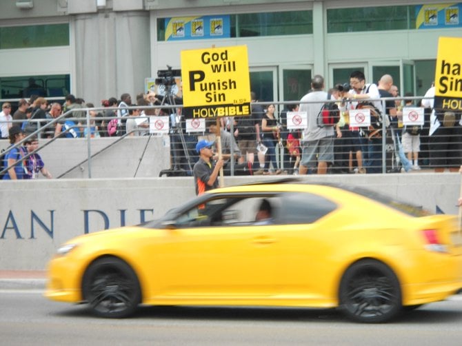 Yellow car matches yellow signs held by Christians at Comic-Con.