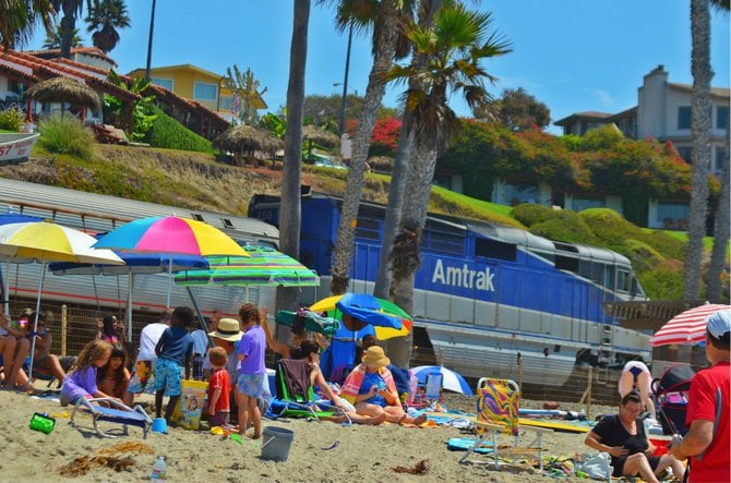 Amtrak passing through San Clemente, with beach goers looking on