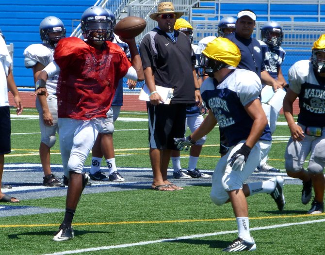 Madison sophomore quarterback Kareem Coles rolls outside with a Warhawks teammate giving chase during practice