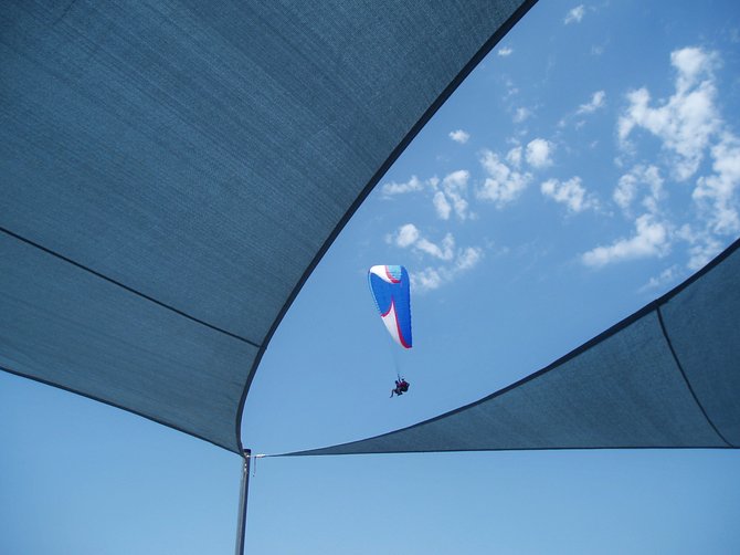 Paragliders sailing over the shade canopy at the Cliff Hanger Café located at the Torrey Pines Glider Port. 