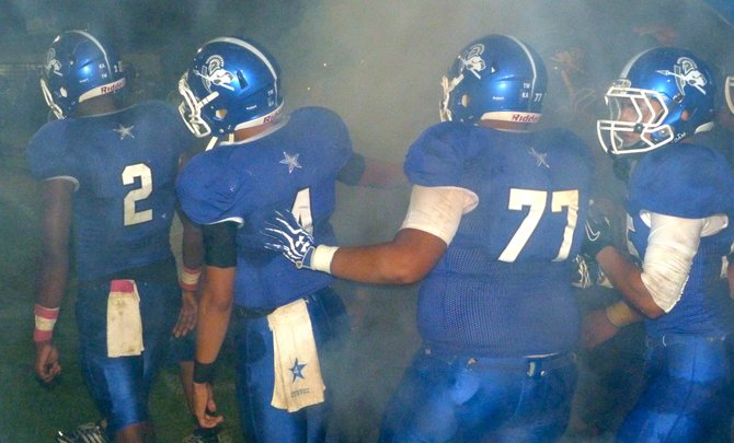 Chula Vista players huddle up amidst smoke before taking the field for the second half