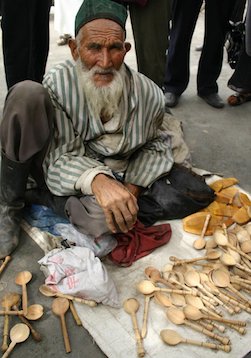 An old man selling spoons painstakingly carved with a pocketknife on the street in Kashgar.