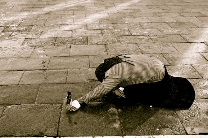 An old Italian woman maintains her begging position for several hours outside St. Mark's Basilica in Venice. Passers-by would either give her money or make the cross sign, while saying a small prayer for her.